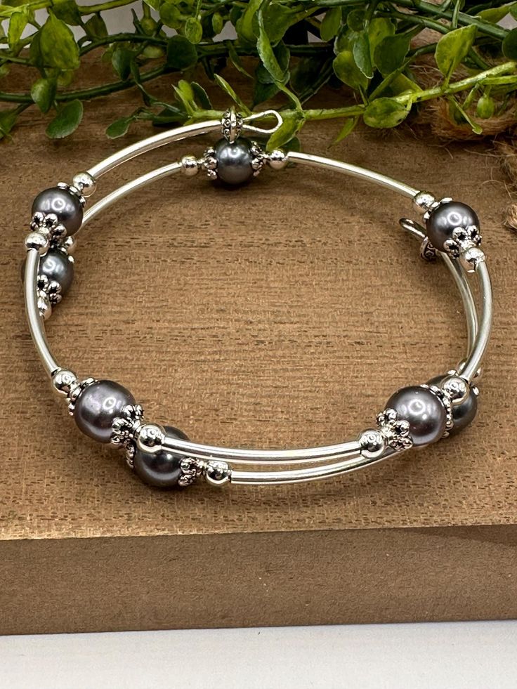 a silver bracelet with skulls and pearls on it sitting next to a potted plant