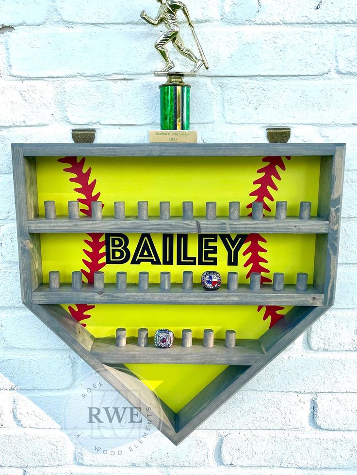 a metal baseball trophy with the word bailey on it in front of a white brick wall