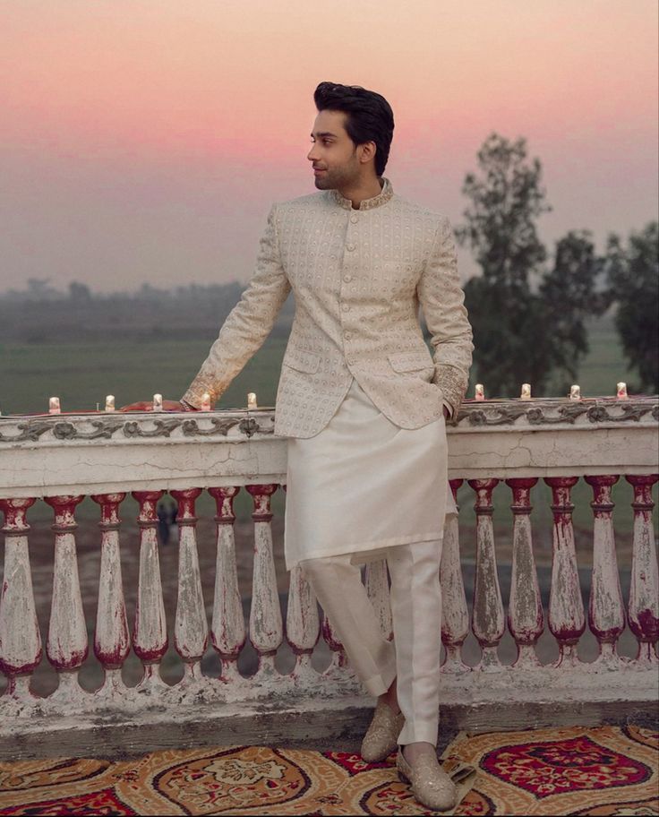 a man in a white outfit standing on a balcony