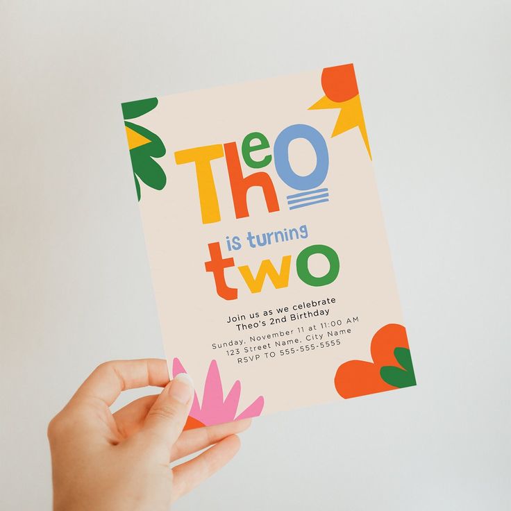 a person holding up a card that says the t o is turning two on it