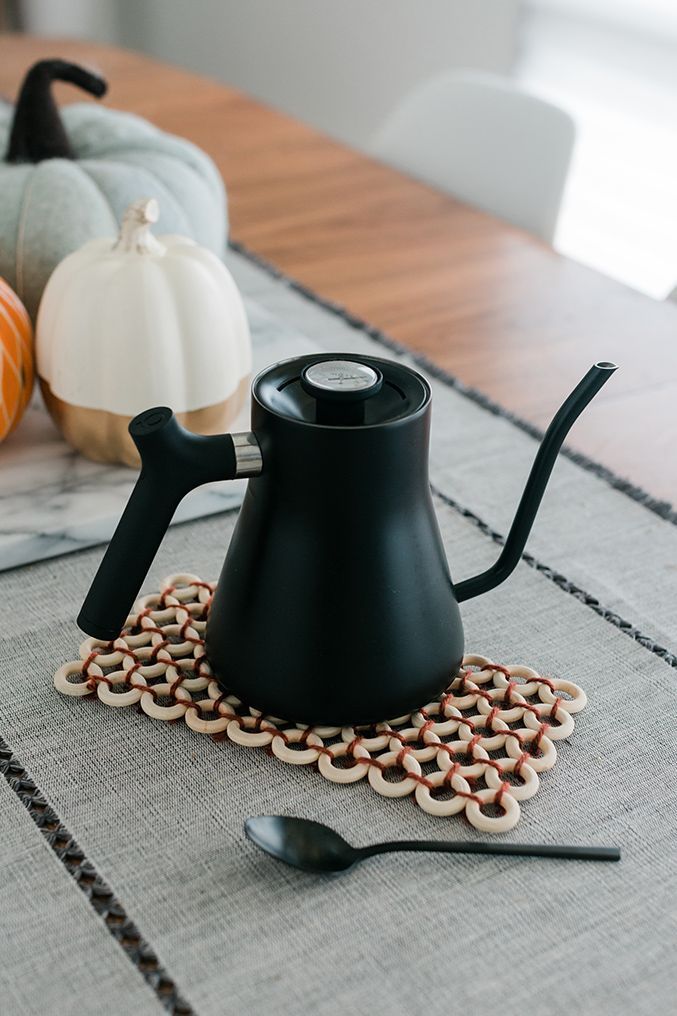 a black kettle sitting on top of a table next to pumpkins and other decorations