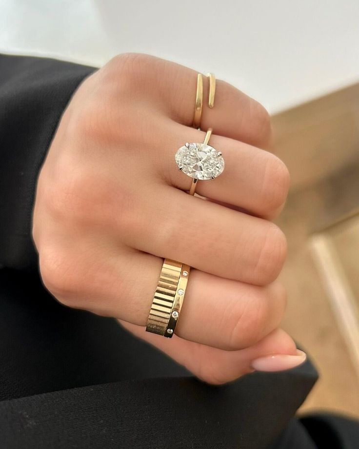 a woman's hand with two gold rings and a diamond ring on her finger