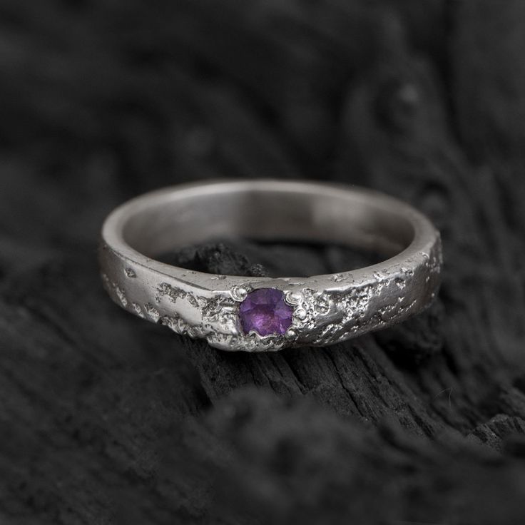 This handcrafted sterling silver ring blends handcrafted quality with understated elegance. The textured band gives it a raw, natural appeal, while the deep purple amethyst adds a touch of refined color. This ring speaks quietly but with character--an ideal choice for those who appreciate thoughtful design and natural beauty. FEATURES & CHARACTERISTICS * Material: High-Quality 925 Sterling Silver * Design : Textured handcrafted ring with purple amethyst * Size: Ring width approx. 3mm wide * Gems Amethyst Gemstone Ring, Silver Ring With Purple Stone, Amethyst Ring Engagement, Beauty Features, Purple Rings, Unique Engagement Ring, Silver Design, Handcrafted Rings, Purple Stones