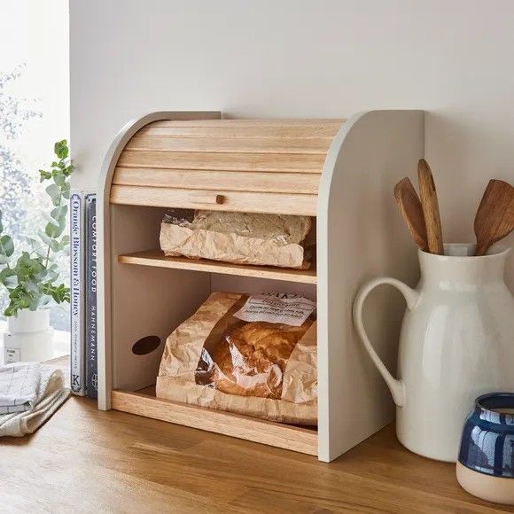 an open mailbox with bread in it on a wooden table next to a vase