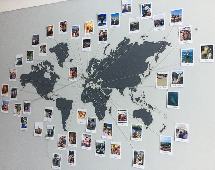 a world map is shown with many pictures attached to the wall and pinned onto it