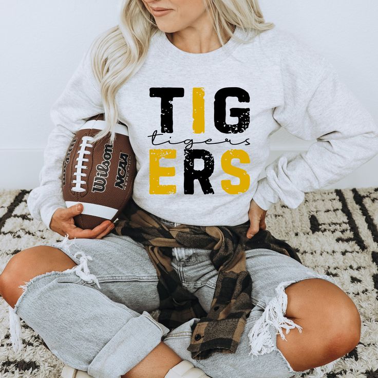 Perfect for any tigers fan! Show your school spirit with this awesome sweatshirt! 50/50 Cotton & Polyester Blend. Gildan Brand Fit: All shirts are unisex fit, true to size, loose fit. Recommend going up 1-2 sizes for an oversized look. Please check the size chart. If you have any questions, please contact us. Please check your address to make sure it is your current address. Care Instructions:  For the best and lasting results, wash in cold water inside out. No bleach. Dry on low heat or hang dry. Do not iron over design.  Returns: Because this item is made to order, all sales are final. No returns are accepted.  Please let us know if you have a problem with your order and we will try to correct the issue.  Shipping: Orders usually ship within 3 business days. Please allow approximately 5 School Spirit Sweatshirt With Team Name For Fall, Fall Sports T-shirt With School Spirit, School Spirit Sweatshirt With Screen Print For Fans, Team Spirit Sweatshirt With Lettering For Fan Gear, Fall Sports School Spirit T-shirt, Team-colored Sweatshirt With Letter Print For School Spirit, Team-colored Letter Print Sweatshirt For School Spirit, Fall Team Spirit Sweatshirt With Screen Print, School Spirit Sweatshirt With Screen Print