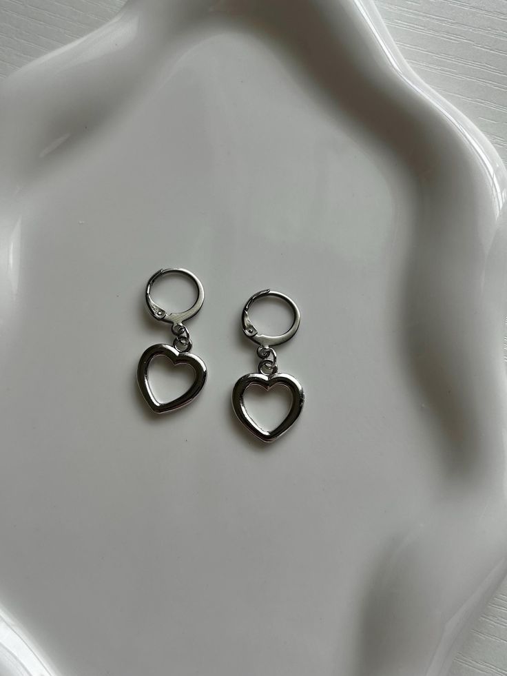 A simplistic earrings pair made with silver heart charms. Subtle enough to wear for the rainiest days, and elegant enough to dress up. Includes 1 pair of earrings (2 hoops). Trendy Sterling Silver Drop Cartilage Earrings, Trendy Dangle Heart Earrings For Pierced Ears, Trendy Dangle Heart Earrings, Trendy Everyday Heart Dangle Earrings, Trendy Pierced Heart Dangle Earrings, Minimalist Sterling Silver Hoop Earrings For Valentine's Day, Trendy Silver Heart Hoop Earrings, Trendy Double Heart Pierced Earrings, Dainty Sterling Silver Hoop Earrings With Heart Charm