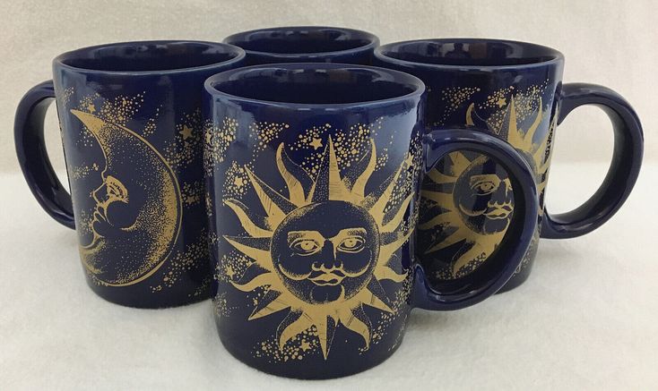 four coffee mugs with sun and moon designs on them, all painted gold or blue