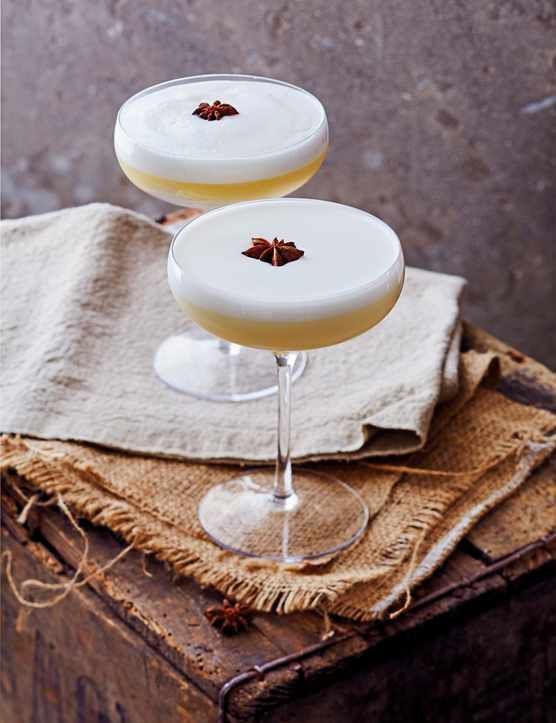 two glasses filled with drinks sitting on top of a wooden table next to a cloth