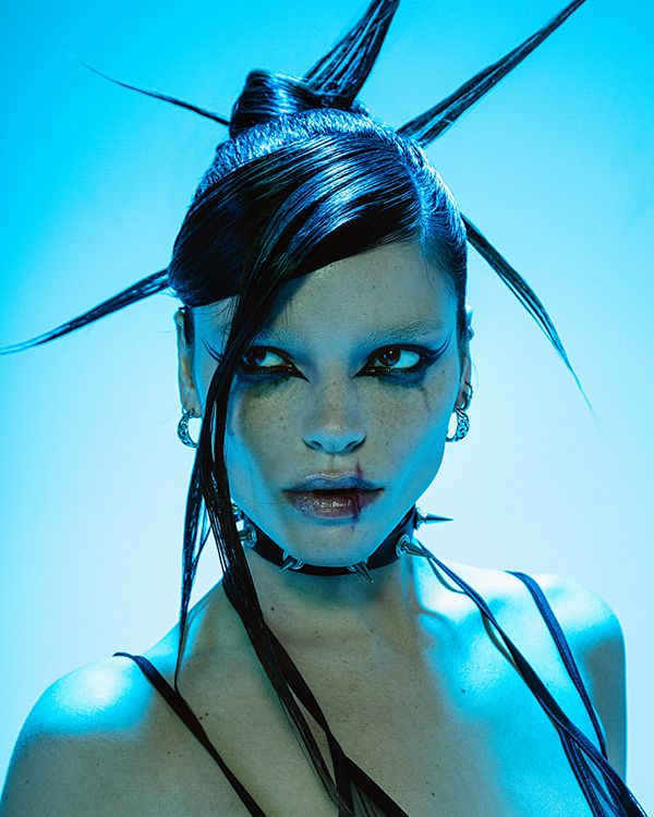 a woman with black hair and makeup is posing in front of a blue background,