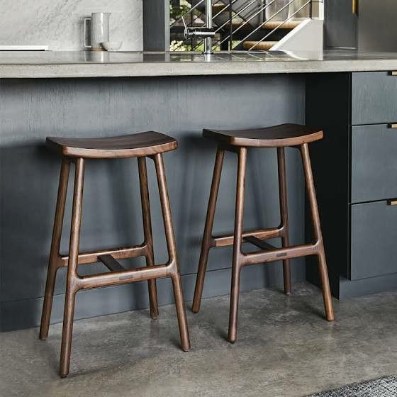 two wooden stools sitting in front of a counter