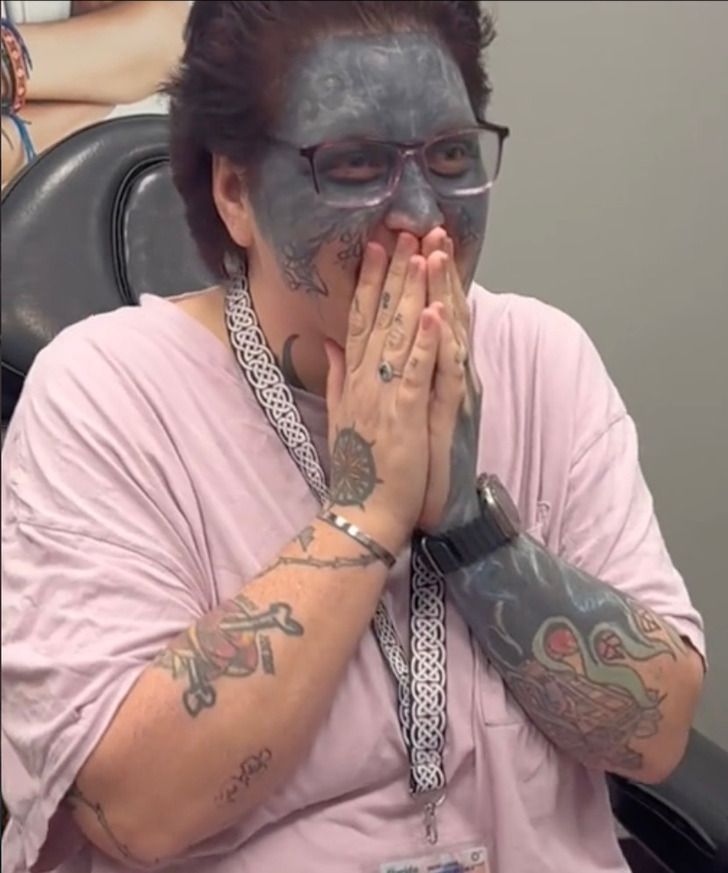 a woman with her face painted in black and holding her hands to her mouth while sitting in an office chair