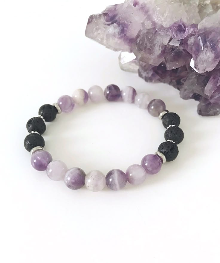 Amethyst Bracelet, Essential Oil Lava Rock Diffuser Bracelet, Calming Bracelet This semi-precious gemstone bracelet is made up of soothing lilac high vibrational purple amethyst  complimented with silver findings. 8mm amethyst and lava rock are strung on strong stretch cord for a comfortable fit for your wrist.    Boost your mood around your wrist wearing lava rock that are uniquely porous. Lava captures and carries essential oil releasing the scent throughout the day like a diffuser for on-the-go aromatherapy. Simply add 1 or 2 drops oil to the lava beads, allow to dry and enjoy the soothing positive benefits.  Lava Rock is a stone of strength and courage and is famous for its grounding and calming qualities. The calming stone of amethyst is known to promote balance, peacefulness, content Unique Crystal Bracelets, Adjustable Crystal Bracelet With Stones For Meditation, Lavender 8mm Beads Jewelry For Healing, Lavender Beaded Bracelets With Natural Stones For Gift, Lavender Beaded Bracelets With Natural Stones, Healing Bracelet With Gemstone Beads And Lava Stone, Healing Lava Stone Bracelets With Gemstone Beads, Adjustable Stone Beaded Bracelets For Meditation, Lavender Bracelet With 8mm Beads For Meditation