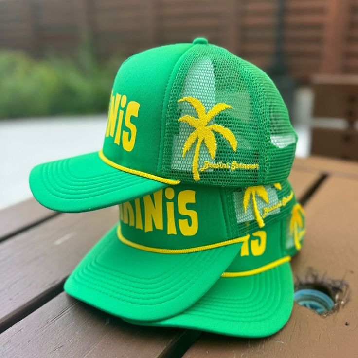 Discover summer’s must-have accessory for beach lovers or if you just want a cool vibe.  Our ‘Bikinis’ trucker hat in green with yellow details is the accessory.  Perfect blend of style and comfort for beach days and casual vibes.  Adjustable snap back fit. This garment is made of 100% polyester Wipe with damp cloth or hand wash  This item features :  Custom design 5 panel foam / mesh construction Rope detail Sweatband inside crown Adjustable snap back closure for easy fit Spring Beach Trucker Snapback Hat, Trucker Snapback Hat For Beach In Spring, Trucker Snapback Hat For Spring Beach, Green Trucker Hat For Beach, Green Trucker Hat For The Beach, Green Trucker Hat For Spring Vacation, Green Snapback Trucker Hat For Vacation, Green Summer Trucker Hat, Summer Vacation Trucker Hat