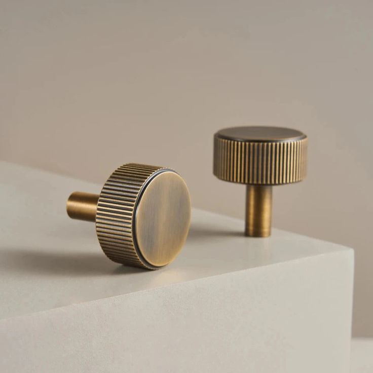 two brass knobs on top of a white surface