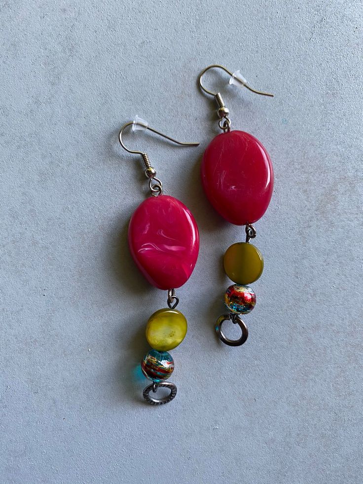 two pairs of earrings with colorful beads hanging from the earwires on a white surface