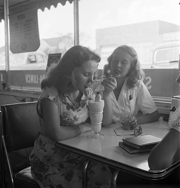 two women sitting at a table with drinks