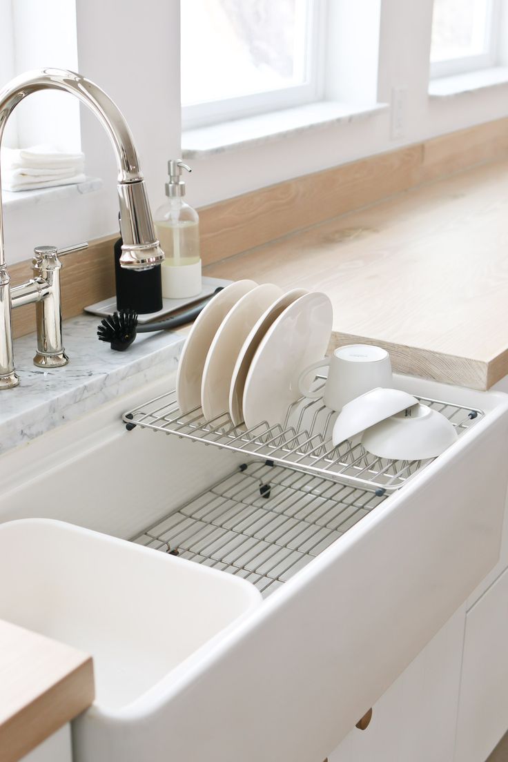 a white kitchen sink filled with dishes next to a window