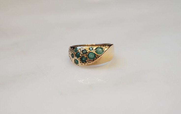 Vintage Mid-Century Circa 1960 Constructed of 14 Karat Yellow Gold Containing 9 Round cut Genuine Earth-Mined Natural Emeralds weighing a total of approximately 0.45 carats *Emerald is the birthstone for those born in the month of May.. Center section of ring measuring approximately 7.3mm in length tapering down at sides to about 2.5mm at back of finger & about 3mm high when on the finger Finger Size 4.75 (Sizing upon request; Additional fee may apply) Weighing 4.8 grams *Sale includes an Apprai Ceremonial Yellow Gold Emerald Heirloom Ring, Heirloom Emerald Ring Stamped 14k, Heirloom 14k Stamped Emerald Ring, Ceremonial Heirloom Yellow Gold Emerald Ring, Antique Emerald Ring In Stamped 14k Yellow Gold, Antique Emerald Ring With Brilliant Cut For Formal Occasions, Antique Emerald Diamond Ring For Formal Occasions, Antique 14k Gold Emerald Ring, Antique Emerald Ring In 14k Gold