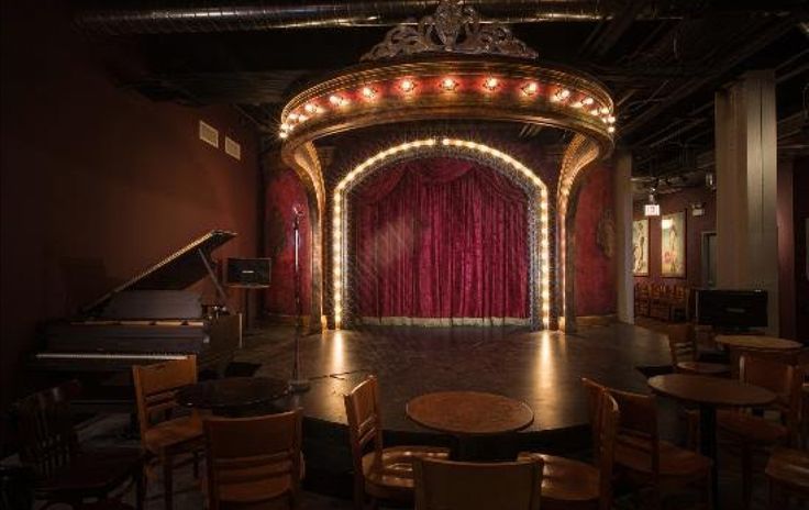 an empty stage is lit up with red curtains