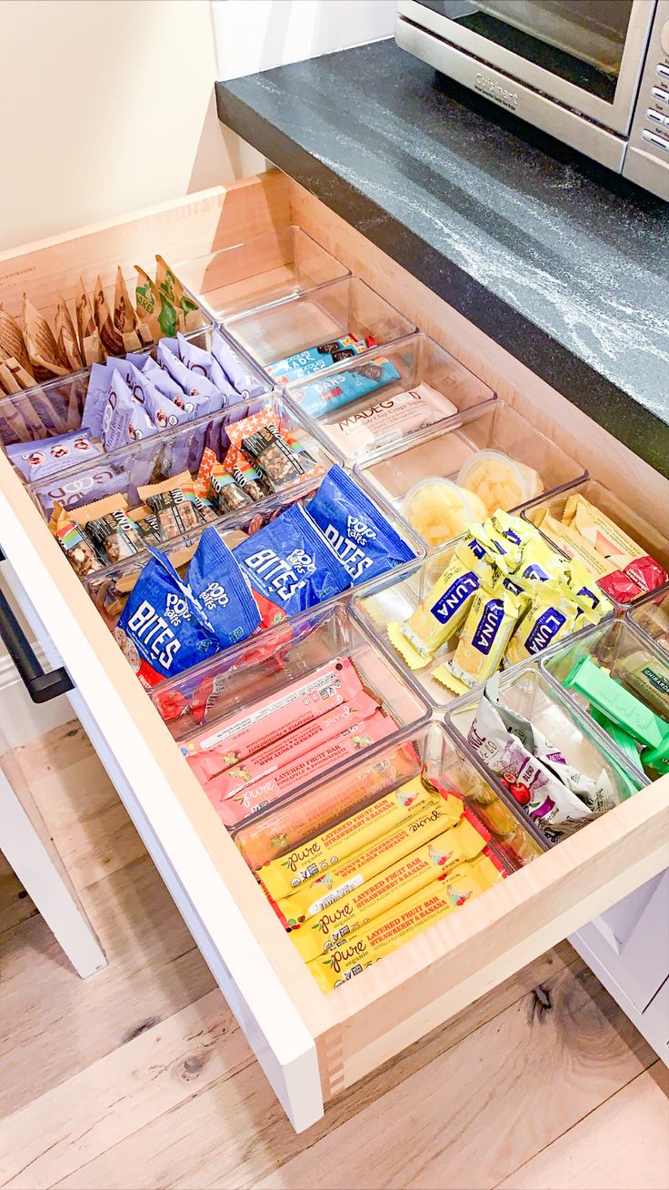 an open drawer filled with snacks and condiments on top of a wooden table