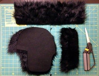 a pair of shears are next to a fur hat and scissors on a cutting board