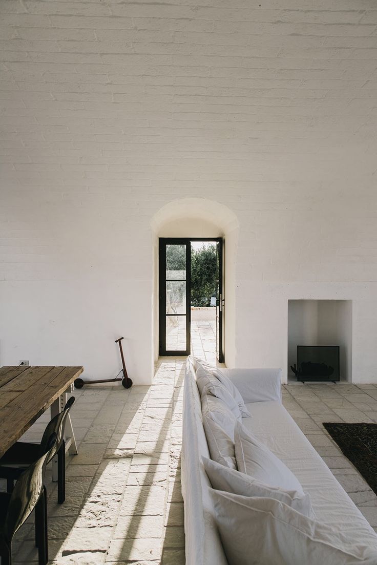 a living room filled with white furniture next to a table and fireplace in a house