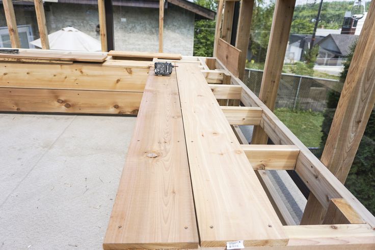 a wooden bench sitting on top of a cement floor next to a building under construction