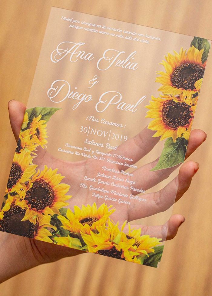 a person holding up a wedding card with sunflowers on it