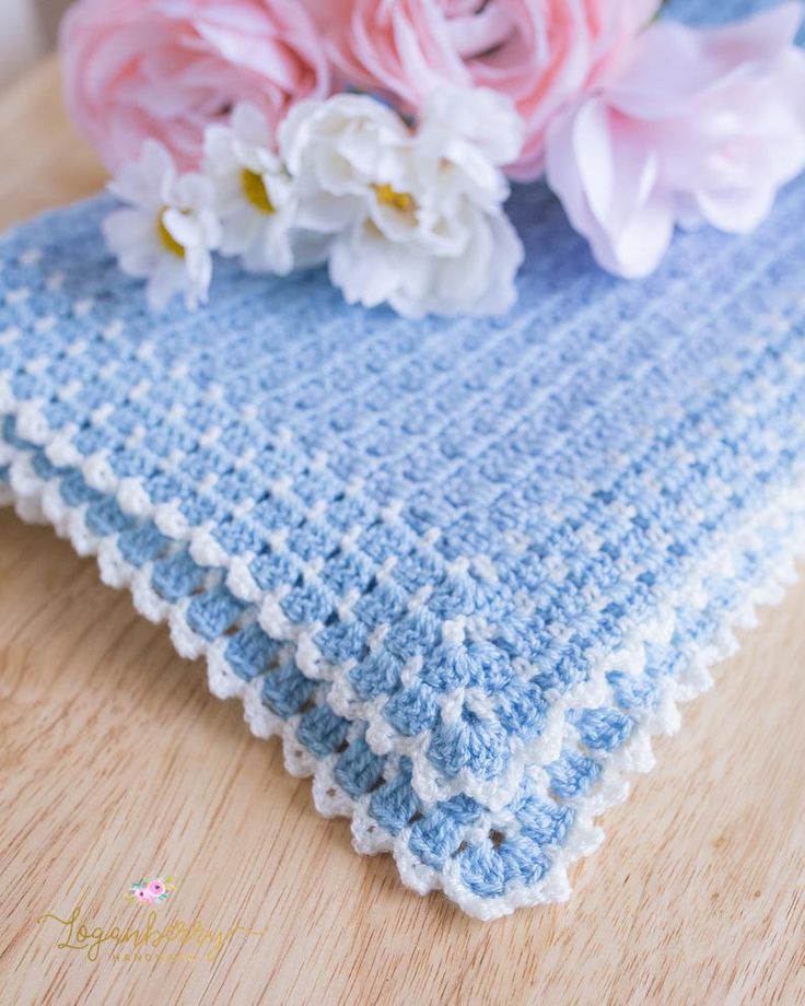 a crocheted blue and white dishcloth with flowers on the table next to it