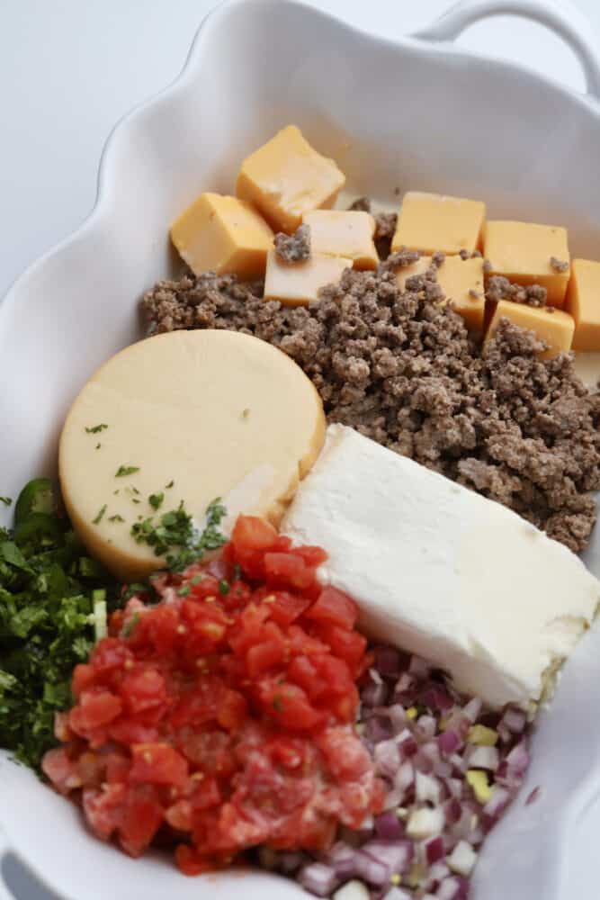 a white bowl filled with meat, cheese and vegetables