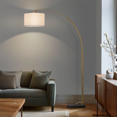 a living room with a couch, coffee table and floor lamp in the middle of it