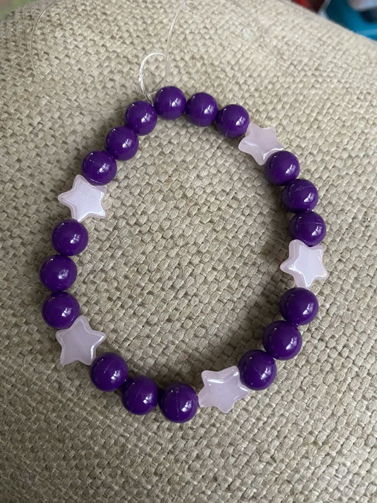 "This beautifully handmade 8mm beaded charm bracelet is strung along clear stretch cord to easily roll onto your wrist. Throughout the bracelet in between dark purple beads are pale pink stars. This bracelet is tied at the end so no need to worry about clips or clasps, this bracelet slides right on! This fits a size 7 inch wrist, but I can adjust if needed. This is a fantastic birthday gift, anniversary gift, Christmas gift, Mother's Day gift, birthday gift, or even a \"just because\" gift! This Braclets Ideas Beaded Purple, Adjustable Star-shaped Jewelry With Spacer Beads, Adjustable Star Shaped Jewelry With Spacer Beads, Adjustable Celestial Bracelets With Round Beads, Adjustable Celestial Bracelet With Round Beads, Adjustable Celestial Beaded Bracelets With Round Beads, Celestial Style Adjustable Beaded Bracelets With Round Beads, Adjustable Beaded Bracelets With Star Charm For Friendship, Adjustable Celestial Bracelets With Star Charm