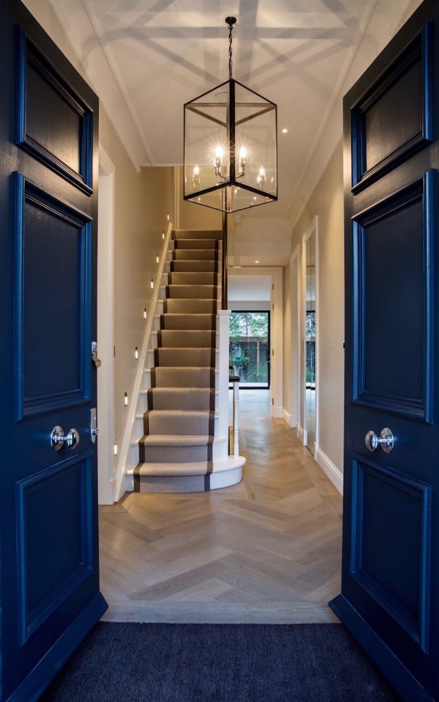 an open door leading to a hallway with stairs and chandelier hanging from the ceiling