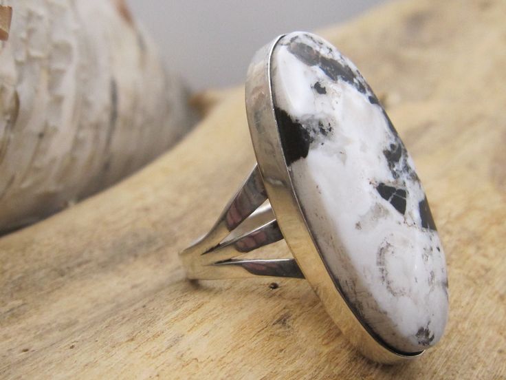 If you're looking for an unadorned, contemporary style statement ring set with a beautiful piece of white buffalo then this ring is for you.  Long, oval White Buffalo cab is 1 3/8" in length, and nice mix of black and white material.  Contemporary bezel setting with triple split shank.  Size 8. Hallmarked RP.   Your interest is appreciated and many thanks for supporting our small business.      WE NOT SHIP INTERNATIONALLY. Returns:  Carefully review the description of the item and the pictures.  If you have any questions, please ask before ordering.  We do not, in general, issue refunds, but may be considered on case-by-case basis.  Refund will not be issued until the item has been received and will be issued minus shipping or other costs as deemed necessary by the seller.  If a refund is Unique White Oval Cabochon Rings, White Oval Ring With Large Stone, Adjustable White Oval Rings, White Oval Adjustable Rings, Unique White Cabochon Rings, White Buffalo, Split Shank, Style Statement, White Material