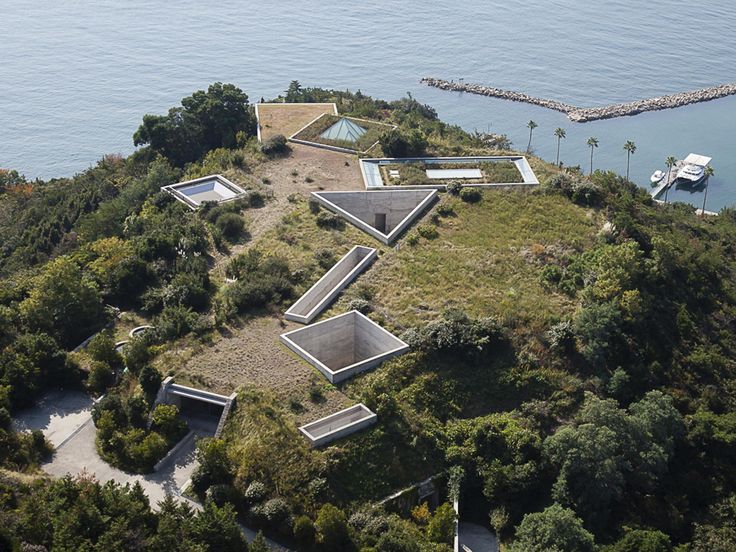 an aerial view of a house on top of a hill with trees and water in the background