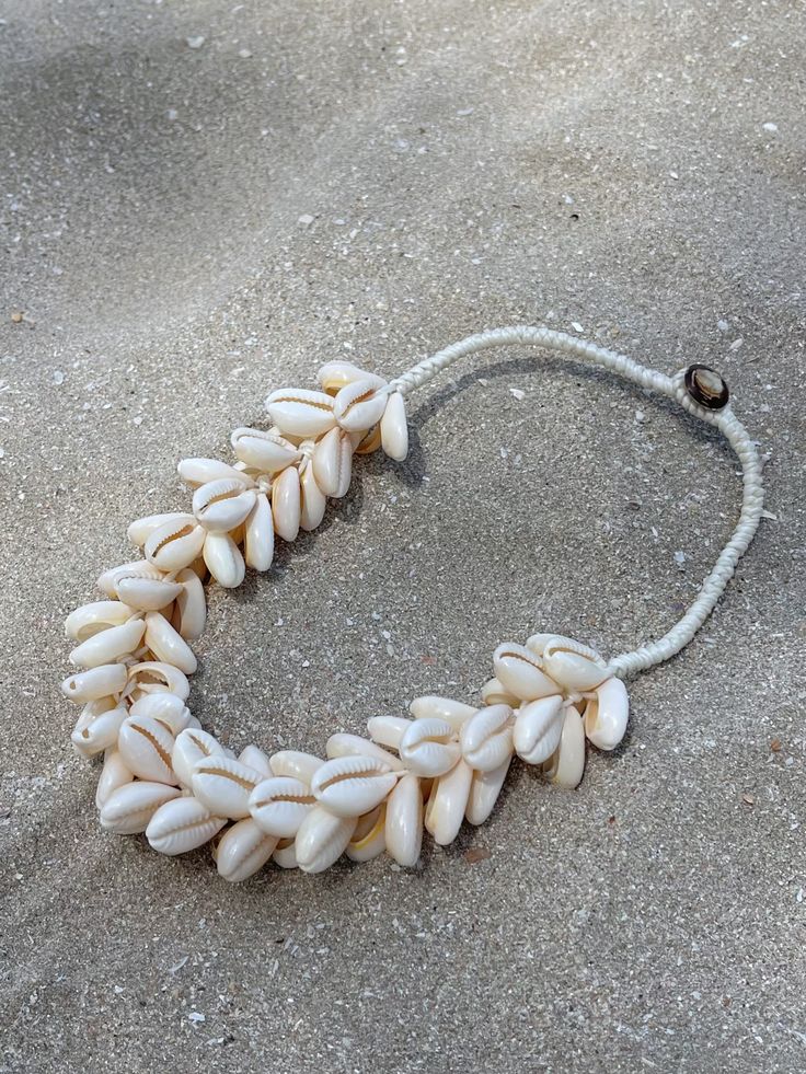 Introducing our new beach accessory: the OCEAN COWRIE SEASHELL CHOKER NECKLACE. Crafted with natural shells sourced, this statement piece beautifully captures the essence of the sea. Each shell is carefully combined to create a captivating and unique representation of oceanic beauty. Perfect for beach outfits, honeymoons, cruises, or resort wear, this choker necklace is a versatile addition to your wardrobe. What sets it apart is our commitment to sustainability and our dedication to working dir Shell Jewelry For The Beach In Coastal Style, Beach Shell Necklace Made Of Mother Of Pearl, Coastal Shell Jewelry For Beach Season, Coastal Shell Jewelry For Vacation, Coastal Style Shell Jewelry For Beach Season, Natural Color Cowrie Shell Necklaces For The Beach, Natural Cowrie Shell Necklaces For Beach, Beach Shell Necklaces In Mother Of Pearl, Beach Shell Necklace In Mother Of Pearl