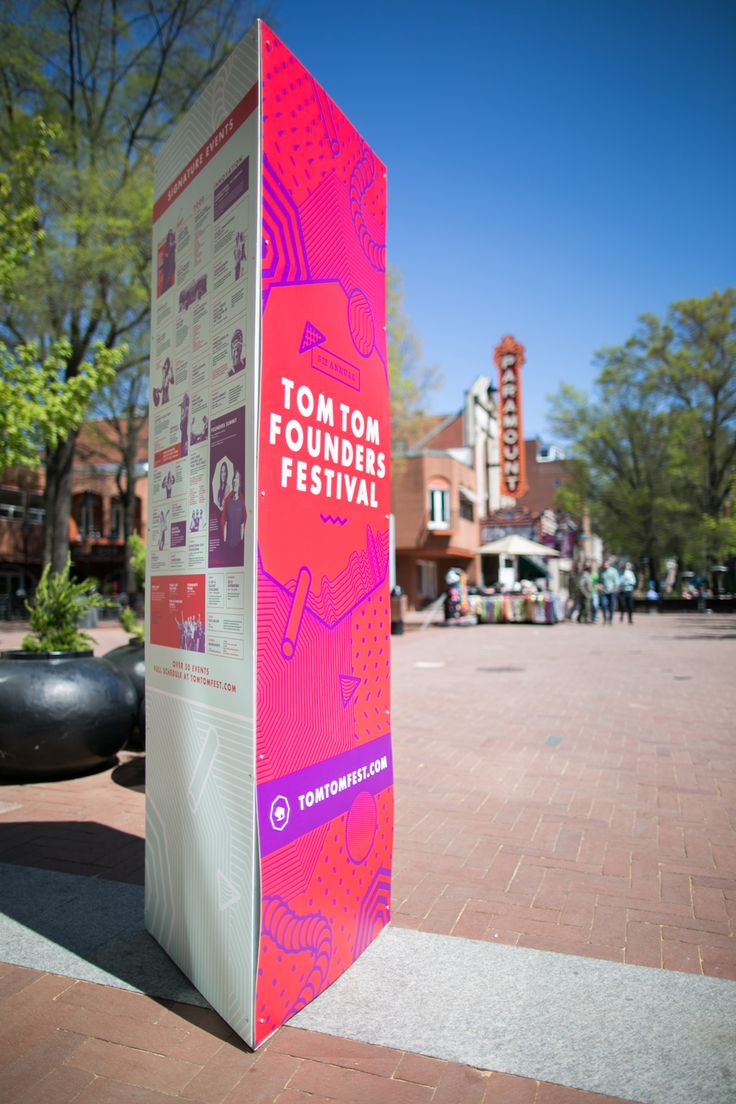 a pink and white sign sitting on the side of a road next to a building