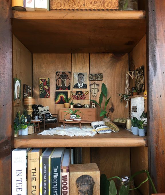 a book shelf filled with lots of books next to plants and pictures on the wall