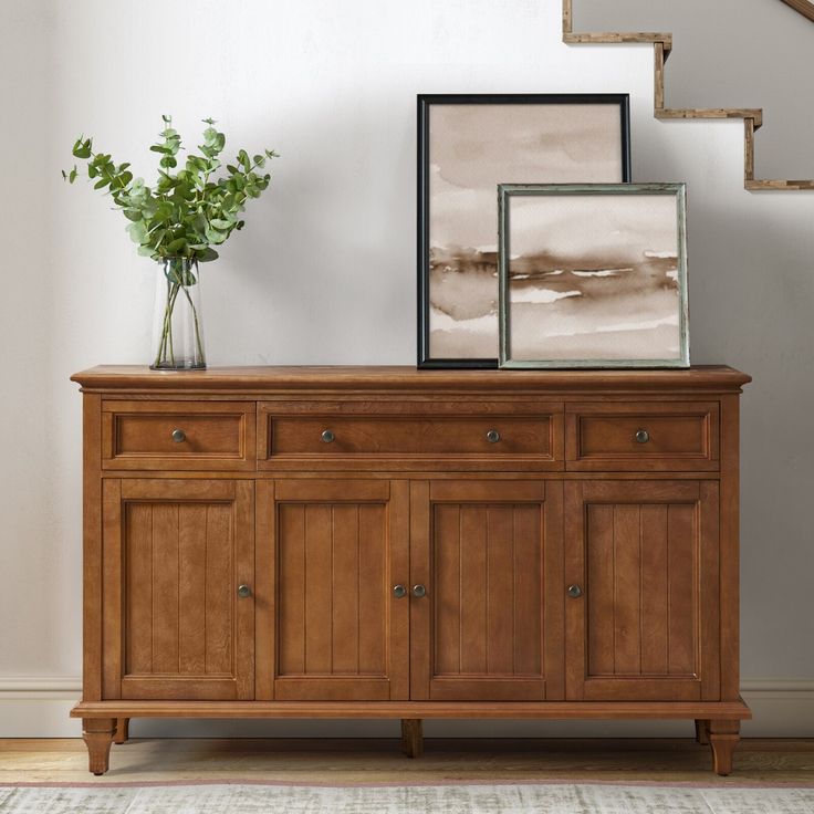 there is a vase with flowers on top of a dresser next to a stair case