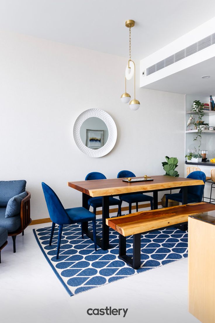 a dining room with blue chairs and a wooden table in front of a white wall