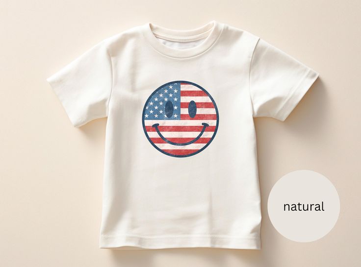 Introducing our Toddler 4th Of July American Flag Smiley T-Shirt, made for Comfort and Style!  :-) DESIGN: This toddler t-shirt features a smiley face colored in with the red, white and blue American flag, sure to show off their love for America! :-) VIBRANT COLORS: Made with high-quality, vibrant ink, the colors on this t-shirt are of exceptional quality and will not disappoint. *{Please note that due to variations in screen resolutions and printing processes, colors may slightly vary from what is displayed on your device. We strive to ensure accuracy in our product images, but slight differences in hue may occur. Rest assured, the charm and vibrancy of this item remains consistent, adding a delightful touch to your wardrobe.} :-) COMFORTABLE FIT: The Bella+Canvas 3001T t-shirt is made of Fun Cotton Shirt For Independence Day, Fun Independence Day Cotton Shirt, Playful T-shirt For 4th Of July With Crew Neck, Playful Crew Neck T-shirt For 4th Of July, Playful White T-shirt For 4th Of July, Cute Cotton T-shirt For 4th Of July, Patriotic Summer Shirt Made In Usa, Cute American Flag Print Short Sleeve T-shirt, Relaxed Fit Summer Tops Made In Usa