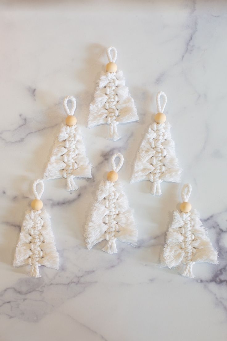 small crocheted christmas trees on a marble countertop with white beads and wood beading