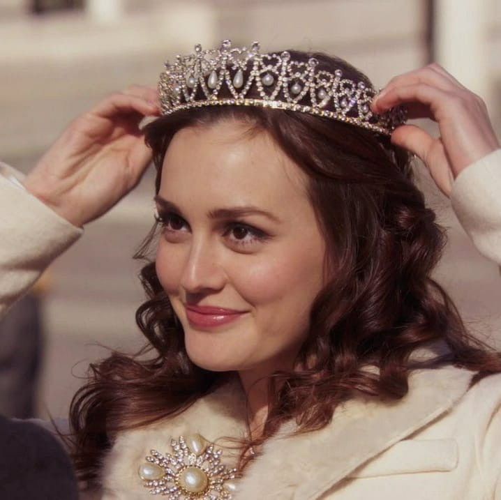 a woman wearing a tiara and smiling at the camera with her hands on her head