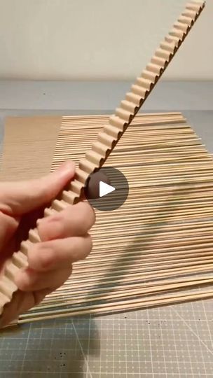 a person is holding a piece of wood and making something out of bamboo sticks on the table