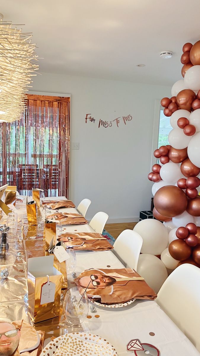 a long table is set with gold and white balloons