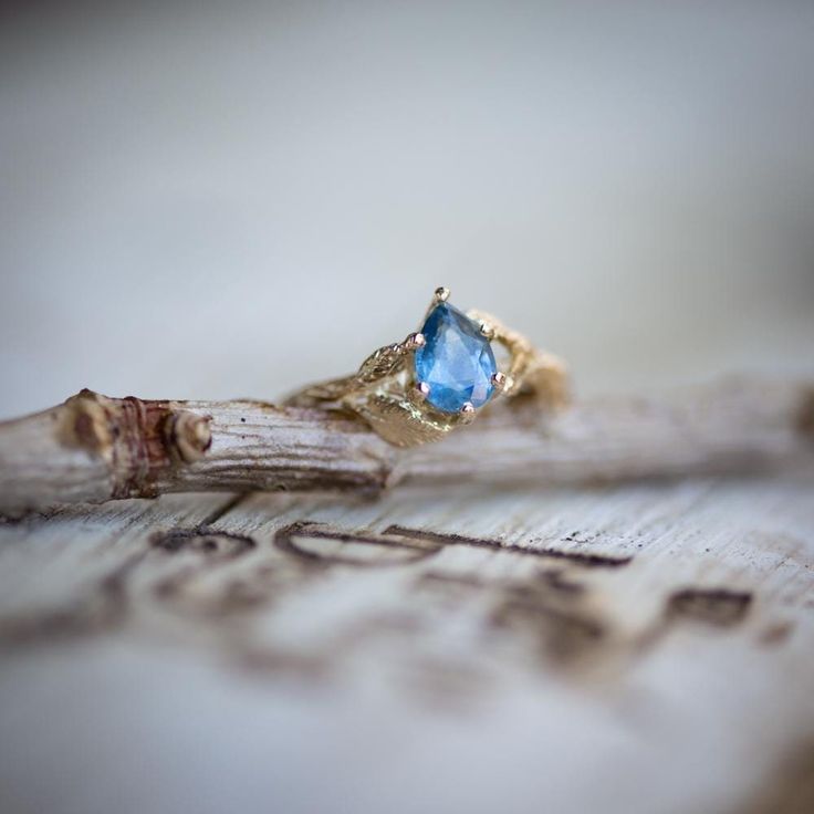 a blue stone ring sitting on top of a piece of wood