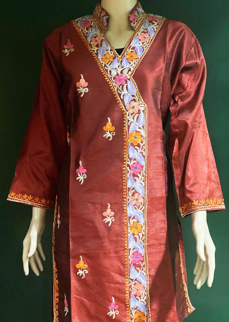 Embroidered Tunic Crafted from raw Silk, designed in Classic Kashmiri Aari embroidery.  Match it with a pair of denims or leggings perfect for Women and Girls a classic tunic that never goes out of fashion. ThisTunic features intricate  embroidery on the neckline, sleeves, the side hem and motif on the front. A combination of vibrant shades with a beautiful play of colors. Color: silk Red Maroon -Color can vary due to lighting. All sizes  are approx.  Size: USA, M  Chest:40 inch.  Shoulder: 17 inch.  Sleeve length: 18 inch  Length: 36 inch. Fabric: Raw Silk- Dry clean or hand wash, iron on low heat. Made in a smoke and pet free home. Made in Kashmir, India Eid V-neck Kurta With Intricate Embroidery, Festive V-neck Dress With Resham Embroidery, Embroidered V-neck Salwar Kameez For Festive Occasions, Traditional Unstitched V-neck Kurta, Traditional Tunic Dress With Zari Work, Traditional V-neck Top With Chikankari Embroidery, Bohemian Embroidered Dress With Dabka Work, Traditional Multicolor Embroidered Tunic Dress, Embroidered Fabric For Straight Kurta With Dabka Work