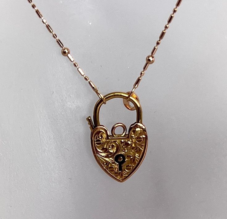 Beautiful example of hand engraved Heart Shape Padlock Charm. This item is 20 millimeters tall and 12 millimeters wide. It is hallmarked and made in 9 karat rose gold and it weighs 1.2 grams The 10 karat rose gold chain is a newer addition and it weighs 1.4 grams. Total weight is 2.6 grams Antique Engraved Rose Gold Necklace, Engraved Rose Gold Necklaces In Fine Jewelry Style, Engraved Rose Gold Fine Jewelry Necklaces, Engraved Rose Gold Necklaces Fine Jewelry, Engraved Rose Gold Fine Jewelry Necklace, Rose Gold Engraved Pendant Jewelry, Luxury Engraved Rose Gold Necklace, Antique Rose Gold Necklace For Formal Occasions, Rose Gold Heirloom Necklace For Formal Occasions