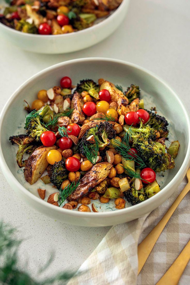 two white bowls filled with vegetables on top of a table